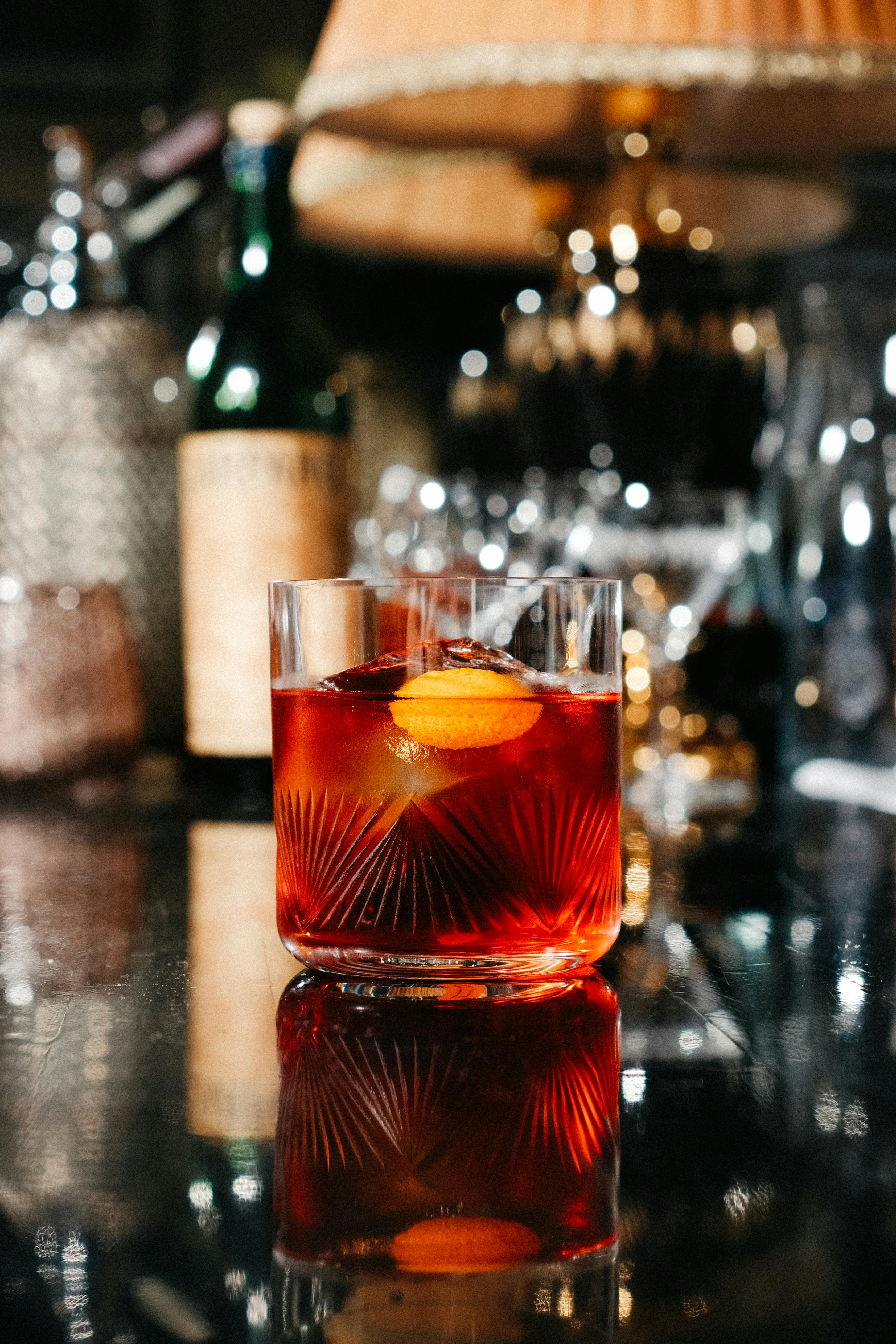 A vermouth cocktail in a stemmed glass, lit in warm amber light